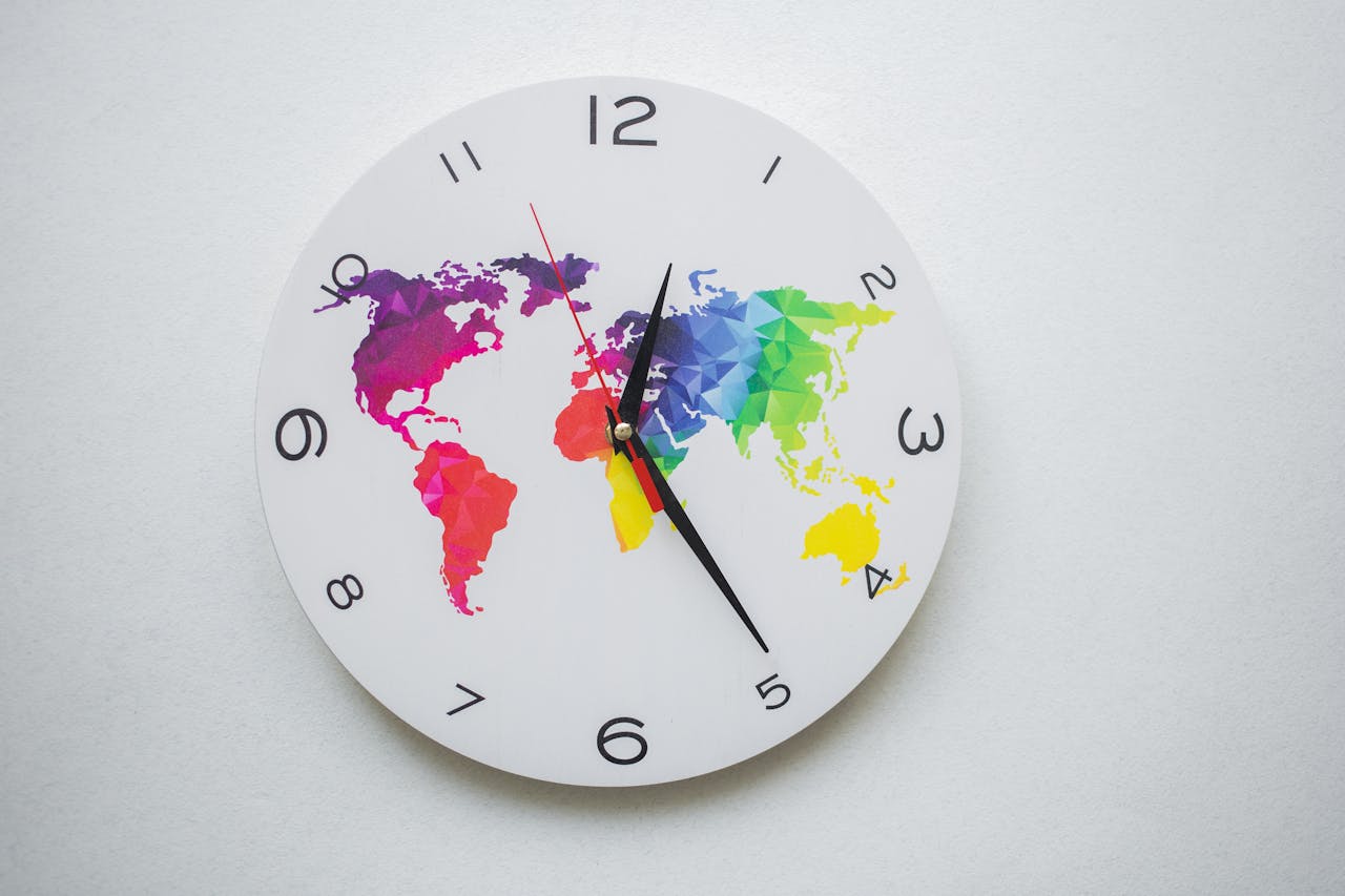 services-04 Round wall clock with colorful world map design and black hands, symbolizing global time.